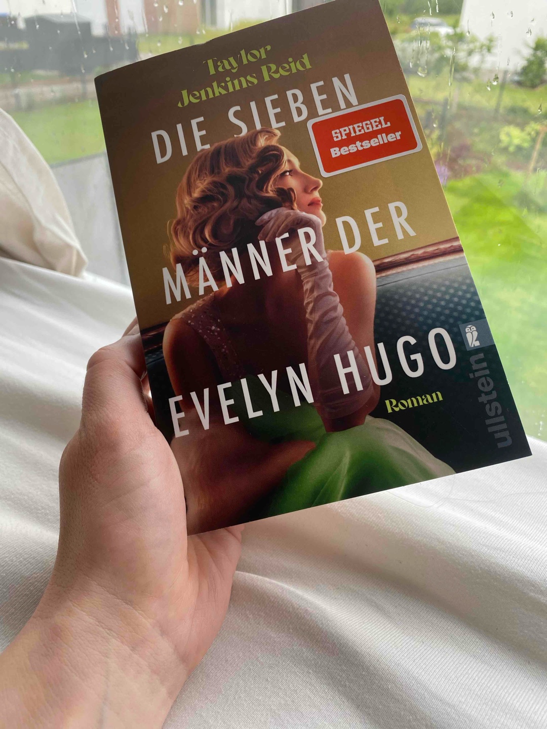 „Die sieben Männer der Evelyn Hugo“ – eine Geschichte über Ruhm, Liebe und den Preis der Wahrheit.

Evelyn Hugo ist eine Hollywood-Legende. Sie hatte alles: Erfolg, Schönheit, Macht. Doch hinter dem Glanz verbirgt sich das Leben einer Frau, die mehr verlor, als sie gewann – und die am Ende nur eines wollte: geliebt werden von der Frau, die sie wirklich liebte und diese Liebe nicht verstecken zu müssen.

Taylor Jenkins Reid erzählt die fesselnde Geschichte einer Frau, deren Aufstieg von Sexismus, Machtspielen und harter Selbstdarstellung geprägt war. Evelyns Weg wirft eine zentrale Frage auf: Wie viel sind wir bereit aufzugeben, um berühmt zu werden – und macht das am Ende wirklich glücklich?